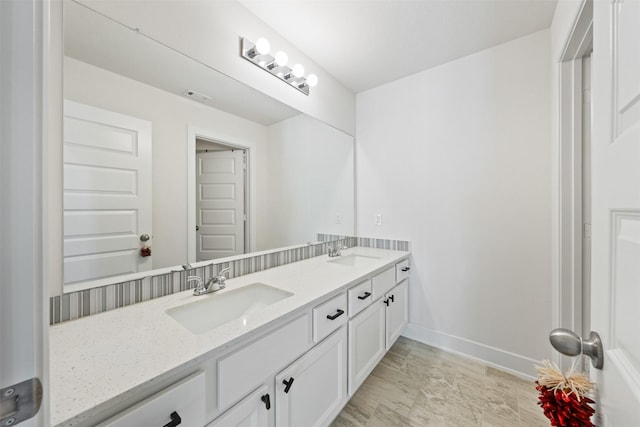 bathroom with double vanity, baseboards, visible vents, and a sink