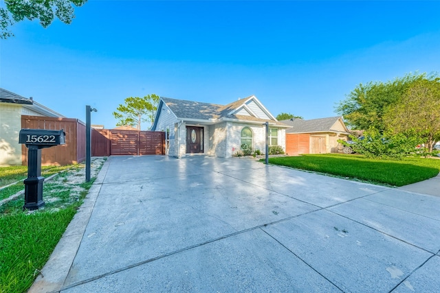 view of front of house with concrete driveway, a front lawn, fence, and a gate