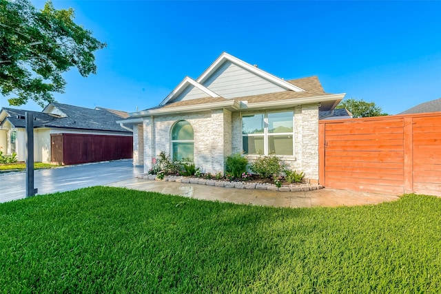 ranch-style house with a front yard, roof with shingles, and fence