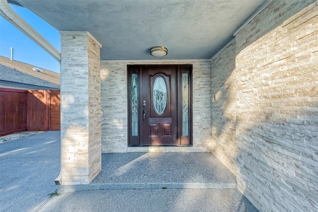 view of exterior entry with brick siding and fence