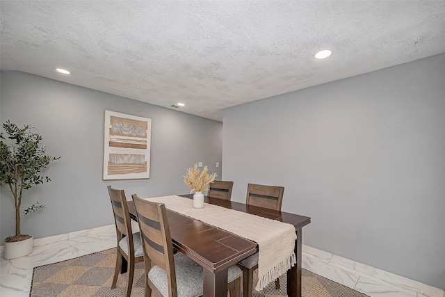 dining room featuring a textured ceiling, marble finish floor, baseboards, and recessed lighting