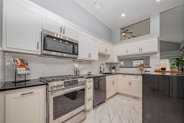 kitchen featuring marble finish floor, dark countertops, appliances with stainless steel finishes, a ceiling fan, and a sink