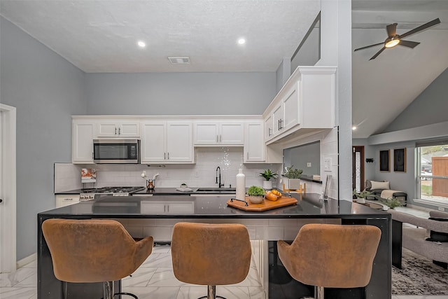 kitchen featuring marble finish floor, stainless steel microwave, a sink, and visible vents