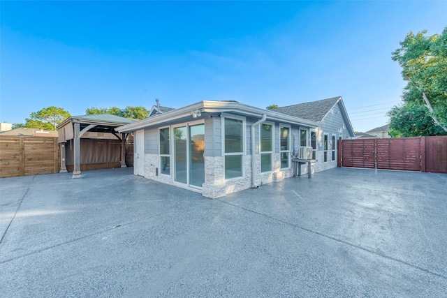 view of property exterior featuring a patio area, a gate, fence, and stone siding