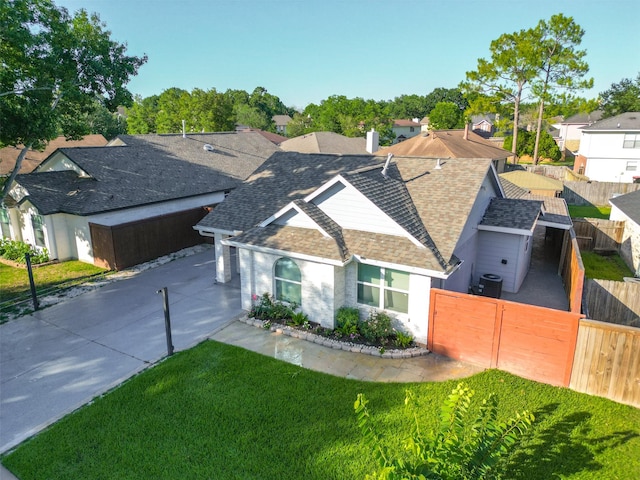 ranch-style house featuring driveway, a front lawn, roof with shingles, and fence private yard