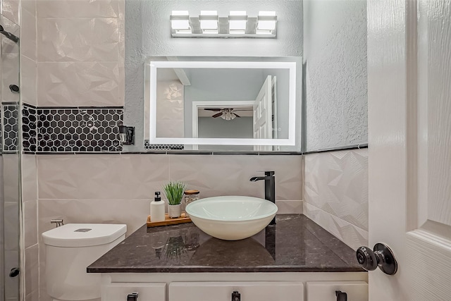 bathroom with a textured wall, vanity, toilet, and ceiling fan