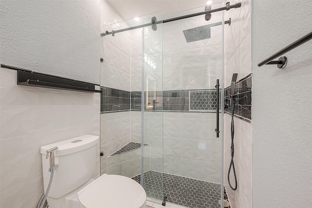 full bath featuring a textured wall, a shower stall, and toilet