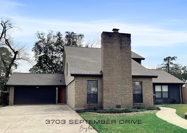 view of front of house featuring a garage, driveway, roof with shingles, a chimney, and a front yard