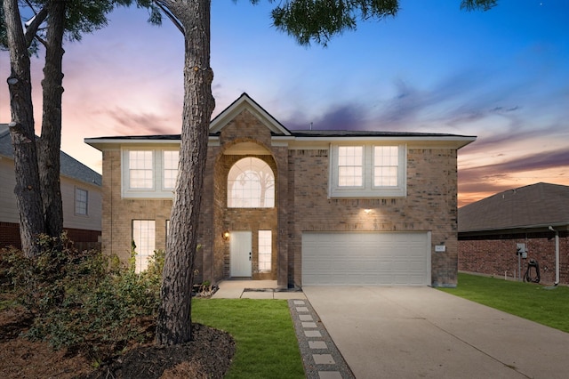 view of front of property featuring a garage, concrete driveway, brick siding, and a lawn