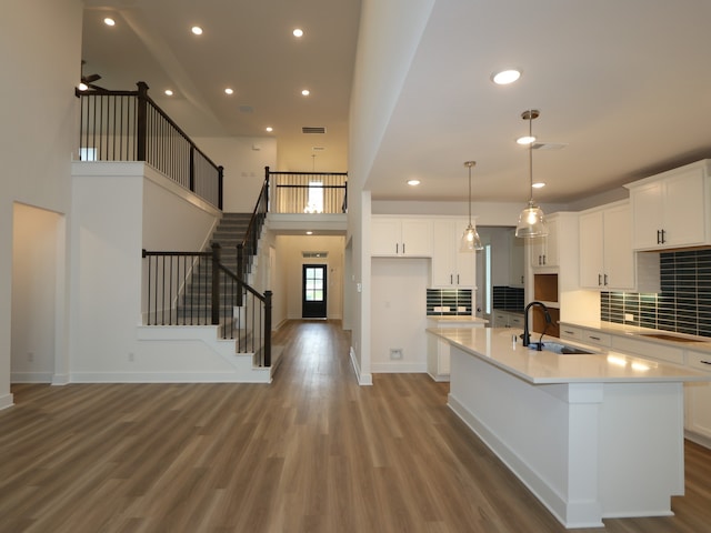 21706 Persian Lake Dr, Cypress, TX 77433 - kitchen with light wood-style floors, recessed lighting, a kitchen island with sink, white cabinetry, and tasteful backsplash