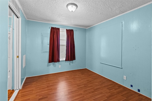 unfurnished room with crown molding, a textured ceiling, and wood finished floors