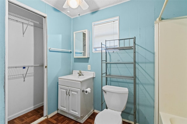 bathroom with ceiling fan, vanity, toilet, and a spacious closet