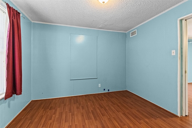 spare room featuring crown molding, a textured ceiling, visible vents, and wood finished floors