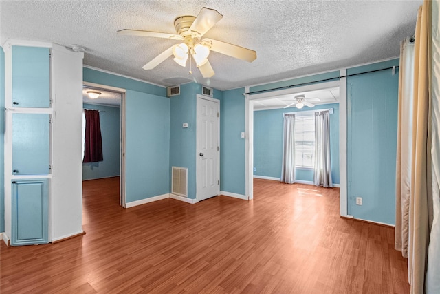 unfurnished bedroom featuring baseboards, a textured ceiling, visible vents, and wood finished floors