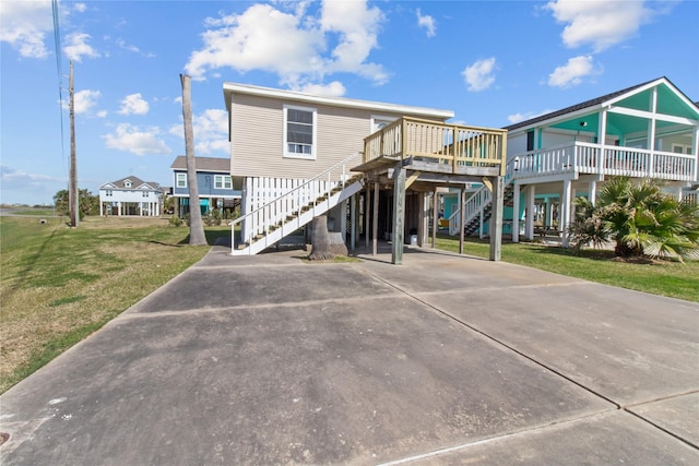 back of property featuring a carport, concrete driveway, a lawn, and stairway