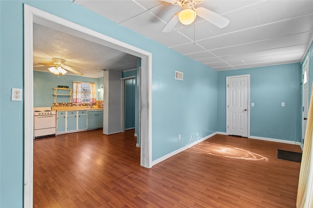 empty room with baseboards, visible vents, ceiling fan, wood finished floors, and a textured ceiling