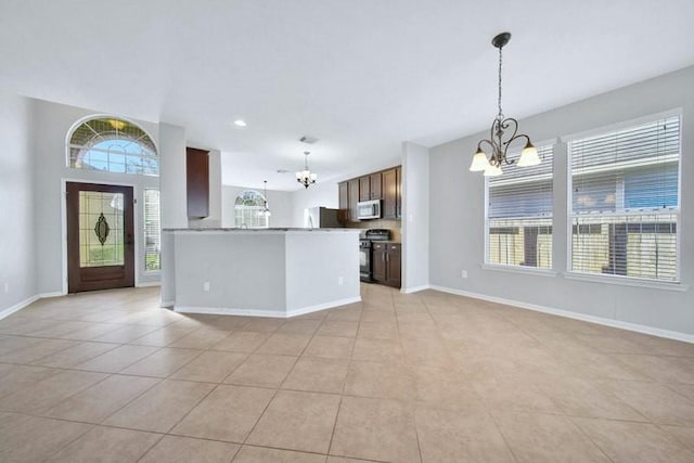 21722 Sierra Long Dr, Richmond, TX 77407 - kitchen with electric range, stainless steel microwave, freestanding refrigerator, an inviting chandelier, and pendant lighting