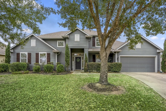 traditional-style home featuring driveway, a front yard, roof with shingles, and an attached garage