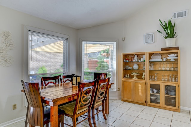 dining area with lofted ceiling, light tile patterned floors, baseboards, and visible vents