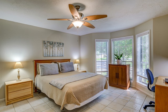 bedroom featuring multiple windows, ceiling fan, a textured ceiling, and light tile patterned floors