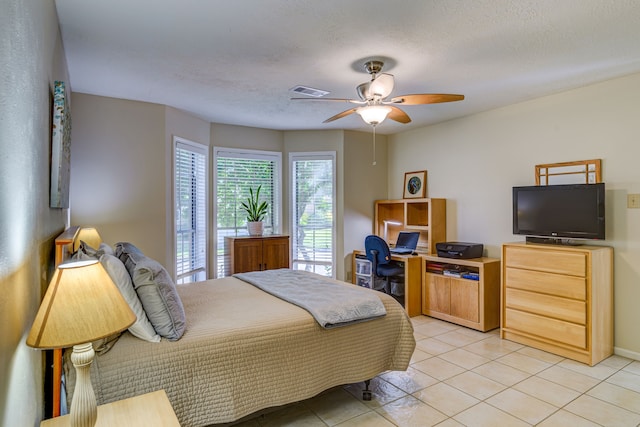 bedroom featuring light tile patterned floors, a ceiling fan, visible vents, and a textured ceiling