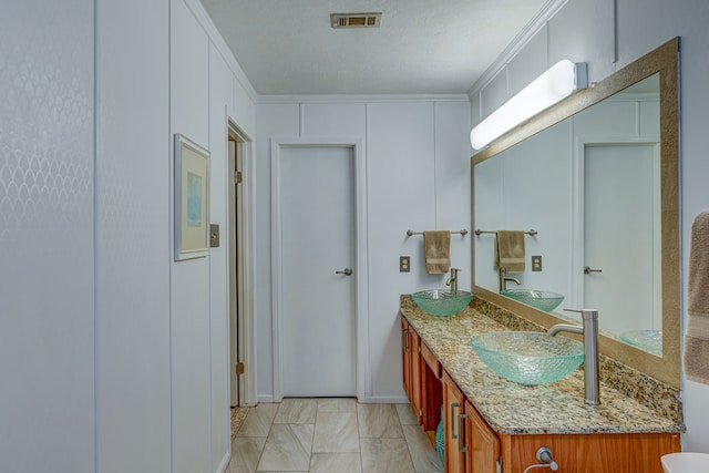 bathroom with crown molding, visible vents, a sink, and double vanity