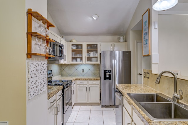 kitchen with a sink, vaulted ceiling, appliances with stainless steel finishes, tasteful backsplash, and glass insert cabinets