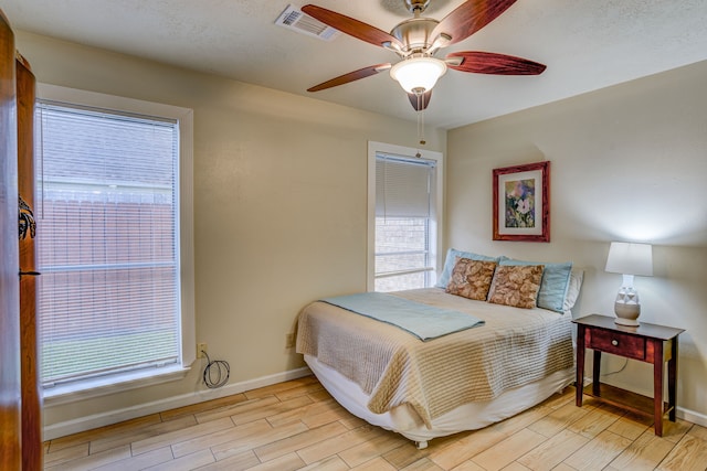 bedroom featuring light wood-type flooring, baseboards, multiple windows, and visible vents