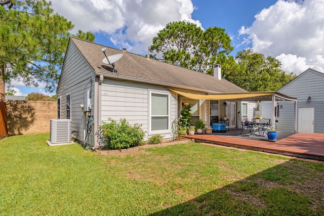 back of property with a deck, central AC unit, fence, a yard, and a chimney