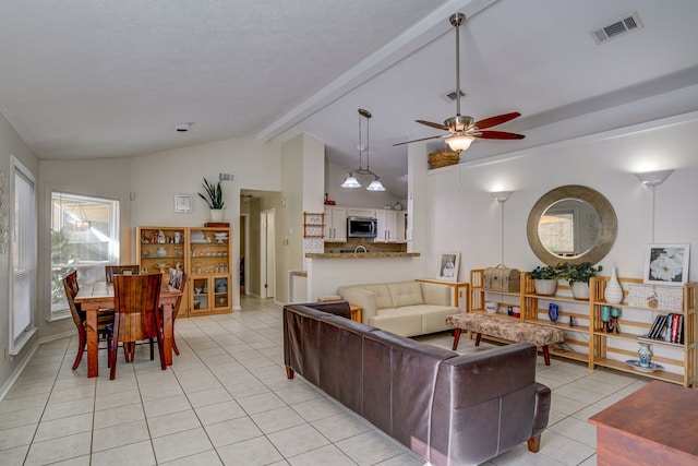 living room with a ceiling fan, visible vents, lofted ceiling with beams, and light tile patterned floors