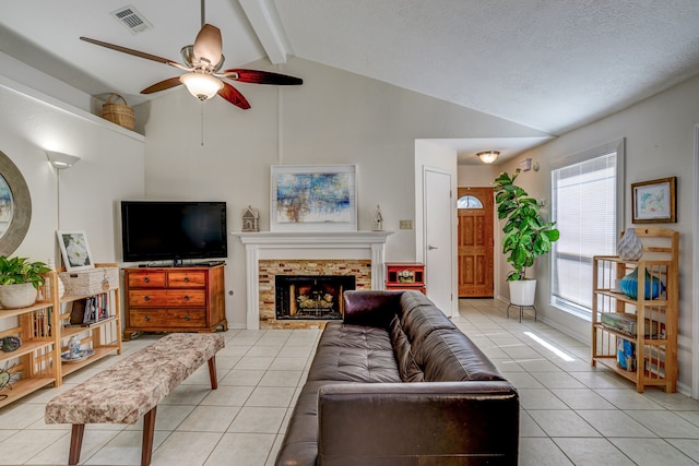 living area featuring light tile patterned floors, visible vents, lofted ceiling with beams, ceiling fan, and a fireplace