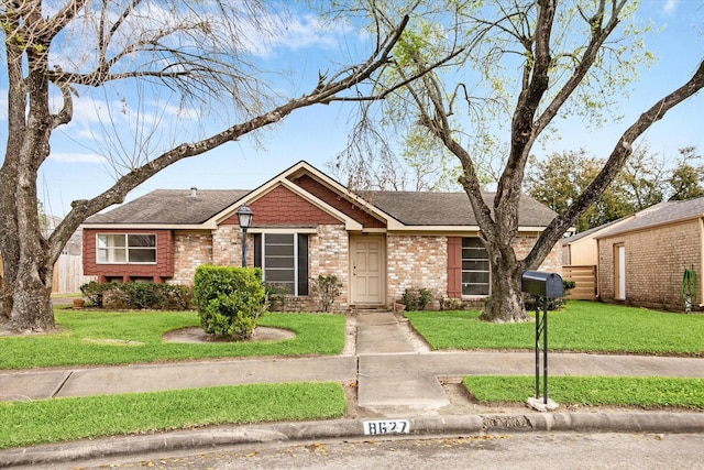 ranch-style house featuring a front lawn, brick siding, and roof with shingles