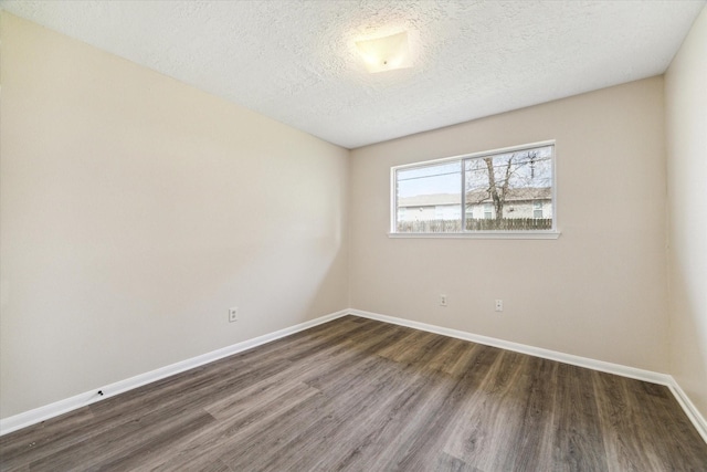 spare room with baseboards, a textured ceiling, and wood finished floors