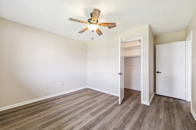 unfurnished bedroom with wood finished floors, baseboards, a spacious closet, a closet, and a textured ceiling