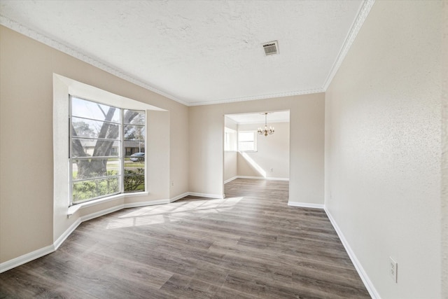 empty room featuring a chandelier, plenty of natural light, crown molding, and wood finished floors