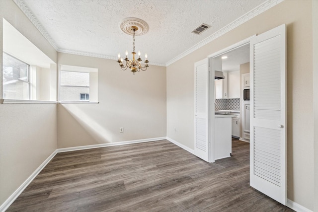 unfurnished room with visible vents, dark wood finished floors, crown molding, baseboards, and a chandelier