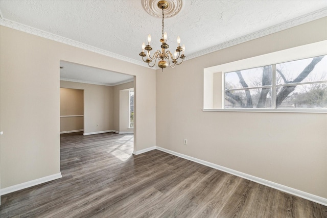 empty room with plenty of natural light, baseboards, an inviting chandelier, and wood finished floors