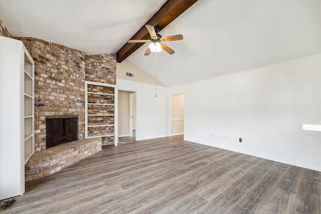 unfurnished living room featuring a ceiling fan, wood finished floors, beamed ceiling, visible vents, and a brick fireplace