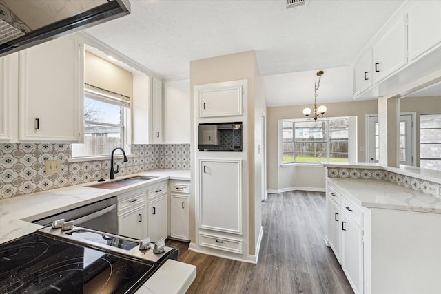 kitchen featuring a sink, tasteful backsplash, white cabinets, and black microwave