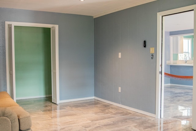 spare room with ornamental molding, a sink, and baseboards