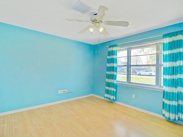 empty room with visible vents, ceiling fan, baseboards, and wood finished floors