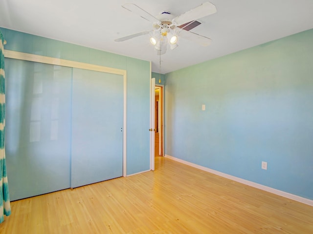 unfurnished bedroom with a closet, ceiling fan, baseboards, and wood finished floors