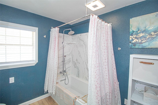 full bath featuring shower / bath combo, wood finished floors, visible vents, and baseboards