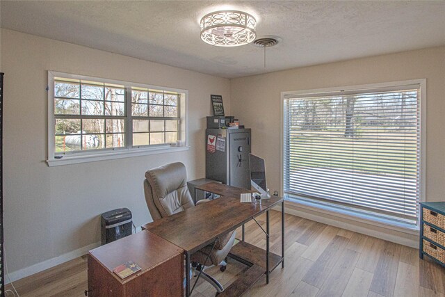 office area featuring baseboards, a textured ceiling, visible vents, and wood finished floors