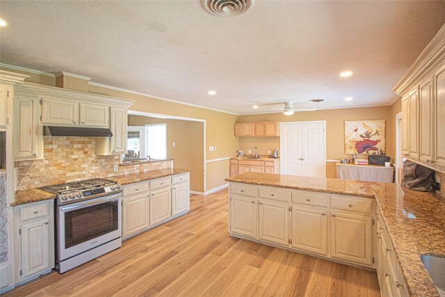 kitchen featuring visible vents, a peninsula, gas range, light wood-type flooring, and under cabinet range hood