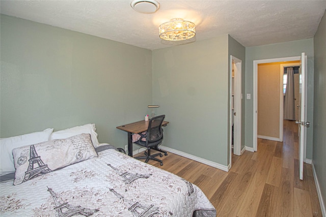 bedroom featuring a textured ceiling, baseboards, and wood finished floors