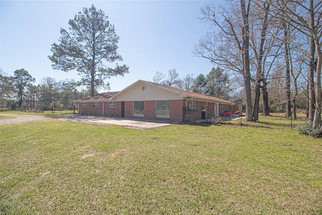 back of house with driveway, a yard, a patio area, and brick siding