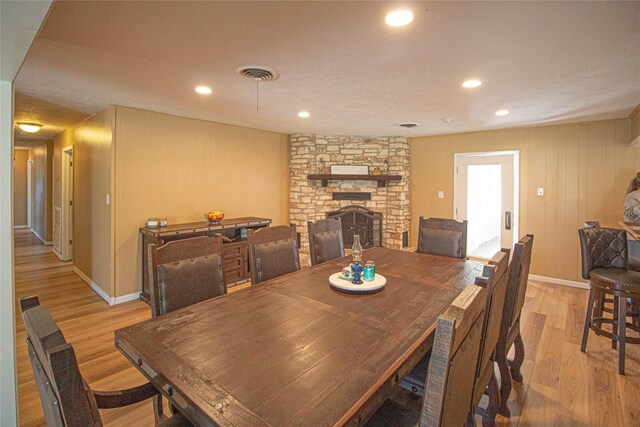 dining space featuring a stone fireplace, light wood-type flooring, visible vents, and recessed lighting