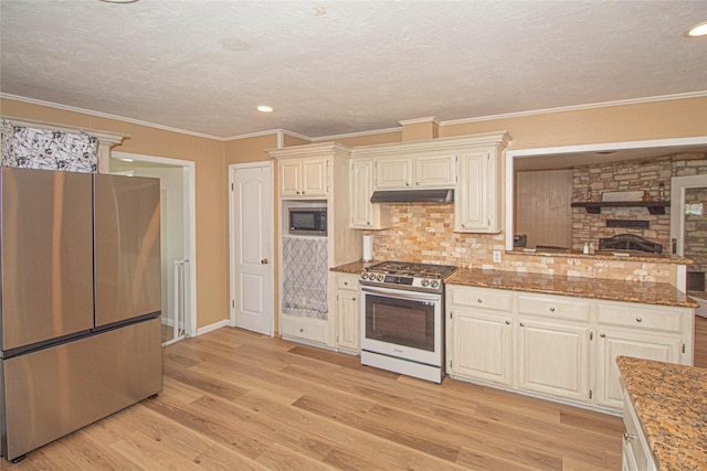 kitchen with decorative backsplash, light wood-style floors, stainless steel appliances, crown molding, and under cabinet range hood