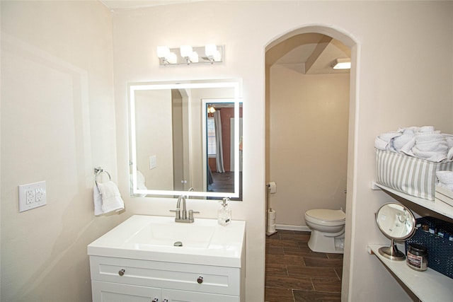 bathroom featuring wood tiled floor, baseboards, vanity, and toilet